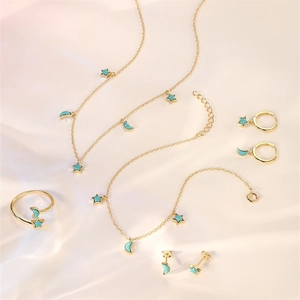 Detailed set of gold star and moon jewelry featuring turquoise stones on a white fabric