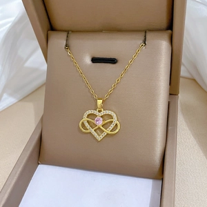Detail of gold heart pendant with pink crystal and small diamonds in a brown velvet box