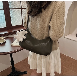 Detail of dark green PU leather shoulder bag with cute white plush bear pendant accessory
