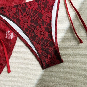 Close-up of dark red floral lace fabric detail on a bikini bottom with side ties