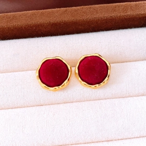 Macro detail of vintage deep red velvet earrings with elegant gold irregular borders