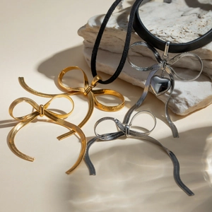 18k gold plated stainless steel bow jewelry set with necklace and pendants on stone base