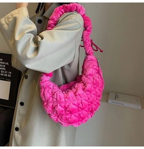 Detail of rose pink velvet cloud bag with quilted texture worn over a beige trench coat