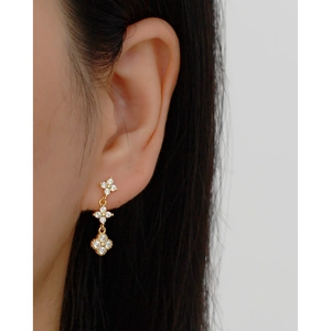Elegant gold clover tassel earrings with sparkling zircon crystals on female model