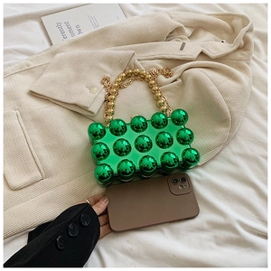 Detail of green bubble texture acrylic bag with golden chain handle on corduroy background