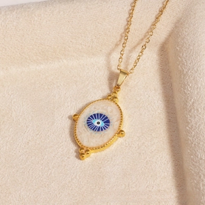 Macro shot of gold devil's eye pendant with blue enamel on a soft beige velvet background