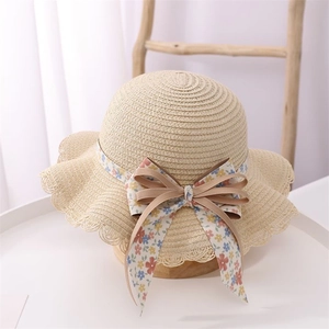 Detailed weave texture of kids beige straw hat with floral bow and wavy brim edge