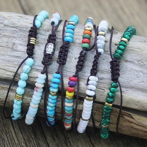 Close-up of woven natural stone bead bracelets in various colors on a wood base