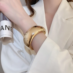 Gros plan d'un bracelet jonc en métal doré minimaliste sur un mannequin en blazer