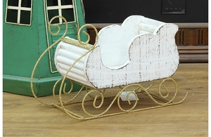 Detail of white wooden Christmas sleigh with golden glitter metal base ornaments