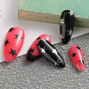 Detail von Stiletto-Kunstnägeln mit schwarzen und rosenroten Sternmustern auf Steinhintergrund