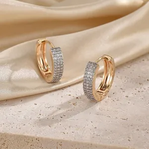 Macro shot of gold-plated hoop earrings with pave-set cubic zirconia on silk and stone