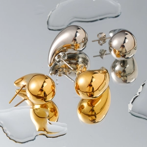Waterproof 18K gold and silver chunky teardrop earrings on reflective surface