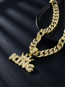 Close-up of golden Cuban chain with sparkling rhinestone KING crown pendant for hip hop style