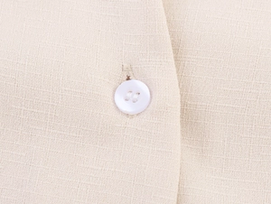 Macro shot of beige linen fabric texture with a white four-hole button detail