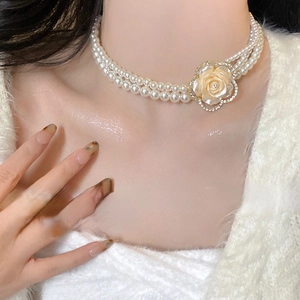 Close-up of a double-layer pearl necklace with a champagne rose pendant on neck