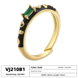 Detailed close-up of gold brass ring with black enamel dots and green rectangle crystal