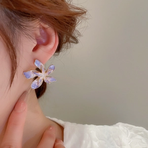 Gros plan de boucles d'oreilles fleurs dégradées violettes portées avec bords dorés