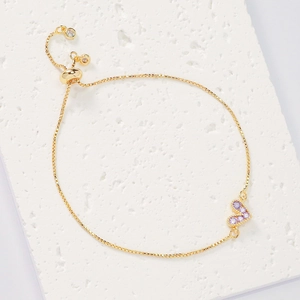 Macro detail of gold adjustable heart bracelet with micro-pave purple zircon stones