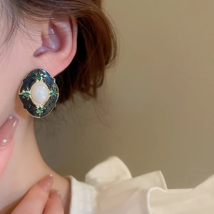 Gros plan de boucles d'oreilles dorées vintage avec opale et émeraude sur un modèle