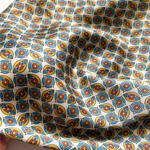 Detail of colorful geometric print fabric in yellow, blue and red on silk-like scarf