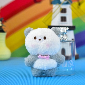 Primo piano di un simpatico ciondolo a forma di orsetto di peluche grigio e bianco.