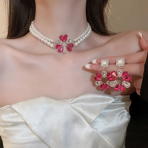 Detail der doppelstöckigen Perlenkette mit rosa Tropfen-Blumen-Ohrringen an Modell