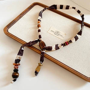 Detail of fabric beaded necklace with wooden and resin beads on a display tray