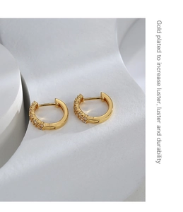 Detail view of asymmetric gold-plated brass hoop earrings with micro-set white zircon stones
