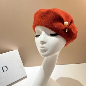 Detail view of brick red wool beret with pearl and gold bead accents on a model head