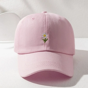 Close-up of fine white daisy embroidery on a light pink cotton baseball cap crown
