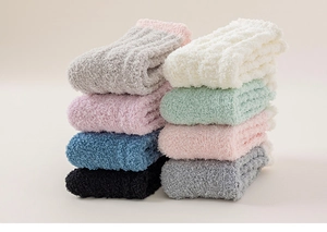 Close-up of a stack of soft coral fleece socks in assorted warm pastel colors