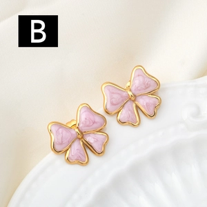 Detailed macro view of pink bow earrings with gold borders on a ceramic dish
