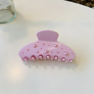 Pince à cheveux rose en acétate avec perles flocons sur fond blanc épuré