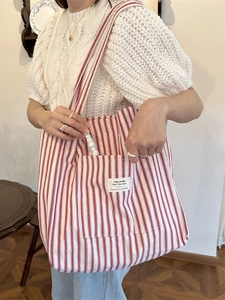 French style red striped canvas tote bag shown on a model in a warm home interior setting