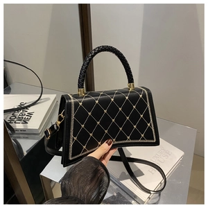 Detail of black quilted PU leather handbag with woven handle and gold star embroidery