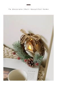 Christmas wreath with LED wooden house, pine cones and berries on a rustic rattan base