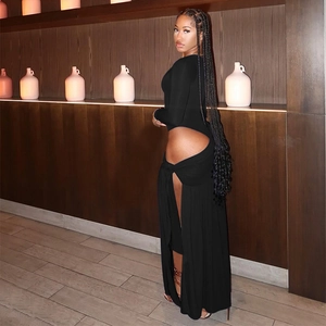 Détail d'une robe noire à manches longues avec découpe à la taille et fente haute à la jambe