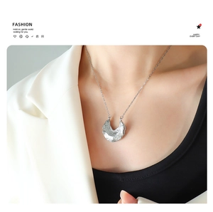 Detail of silver hammered texture irregular circular pendant necklace worn on neck