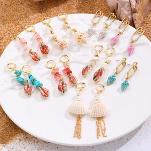 Colección detallada de pendientes bohemios de concha dorada y estrella de mar en la arena