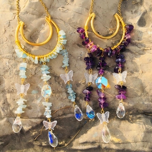 Detail of natural crystal suncatchers with moon pendants and gold woven wire accents