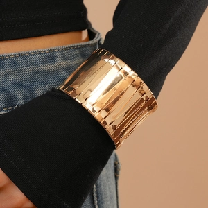 Detail of wide layered gold cuff bracelet with high-polish metallic finish on wrist