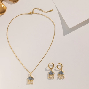 Macro detail of gold cloud necklace and teardrop crystal earrings on white backdrop