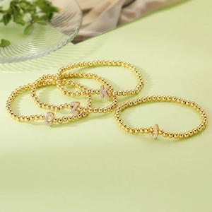 Detail of four gold beaded bracelets with micro-paved zirconia K, Z, C, J letter charms