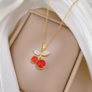 Detail of red cherry pendant with sparkling white crystals on a gold-tone chain