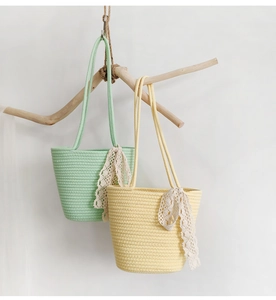 Detail of woven cotton rope bags with lace bows hanging on a branch in natural light
