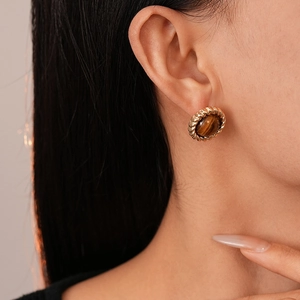 Boucles d'oreilles rondes vintage dorées avec pierre œil de tigre sur modèle féminin