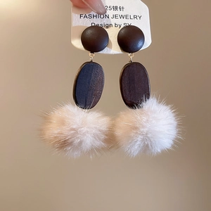 Detail of vintage earrings with S925 silver needles, wood texture and fluffy pom poms