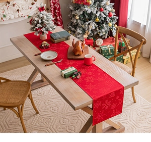 Close-up of red Christmas table runner featuring delicate snowflake jacquard patterns