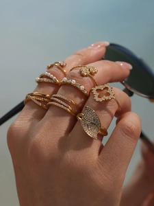 Close-up of gold layered rings with pearls and sparkling zircon on a female hand